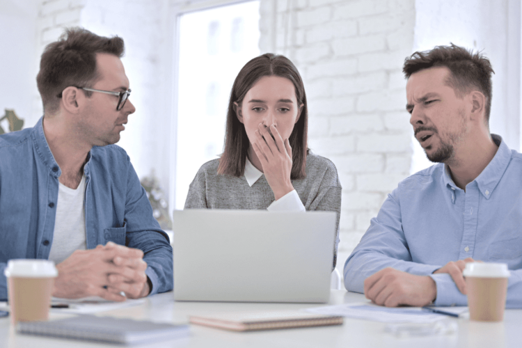 Three colleagues sit around a table, visibly concerned about a sudden problem they have to deal with, highlighting the challenges of team adaptation and the importance of learning how to develop your team to handle unexpected changes effectively.