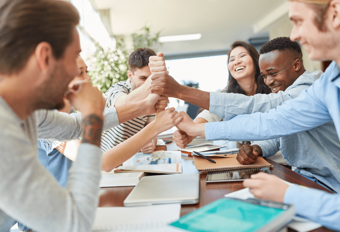 A motivated team showcasing teamship by creating a chain with their hands and committing to working together to overcome challenges and obstacles. 